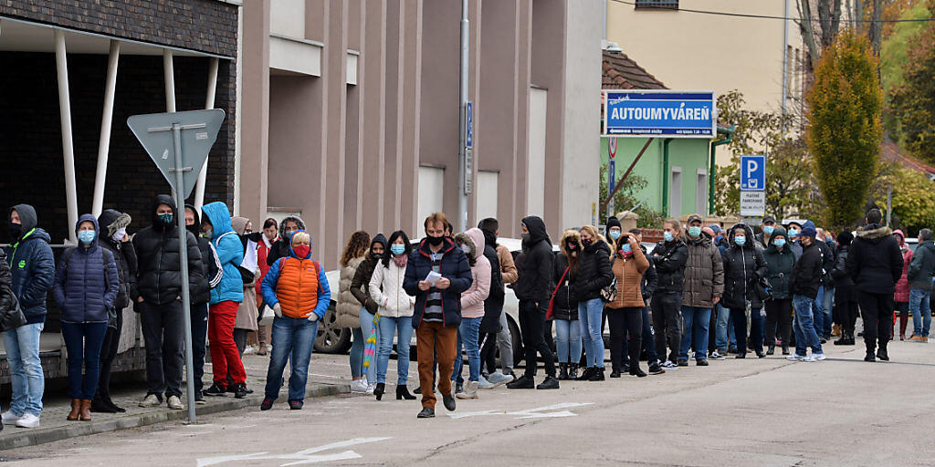 Zahlreiche Menschen mit Gesichtsmaske warten in einer Schlange, um sich auf das Coronavirus testen zu lassen. Foto: Edmund ÷rzsik/TASR/dpa