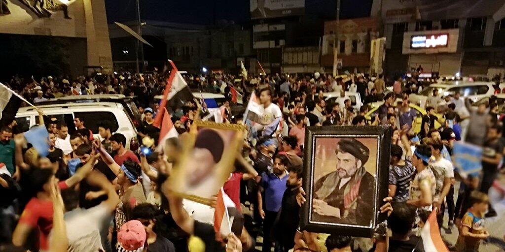 Anhänger schiitischen Predigers Moktada al-Sadr feiern auf den Strassen in Bagdad schon seinen Wahlsieg bei den Parlamentswahlen - obwohl das offizielle Endergebnis noch nicht feststeht.
