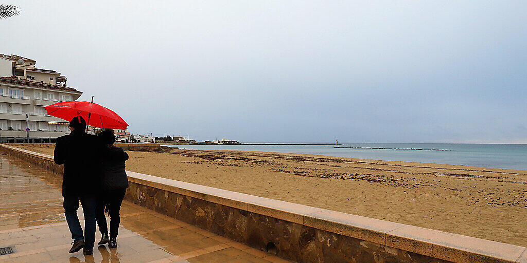 Ein Paar spaziert mit einem Regenschirm am Strand von Palma entlang. Foto: Clara Margais/dpa