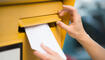 Woman's Hands Inserting Letter In Mailbox