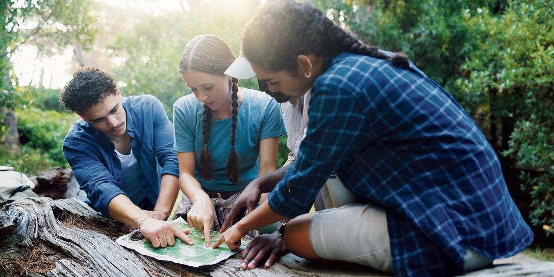 Map, nature and group of friends hiking in forest with route plan for adventure together. Travel, outdoor and people with paper guide for trekking in woods on weekend trip for discovery or journey.