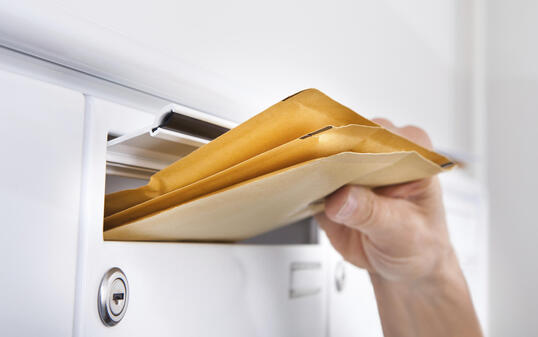 Postman Putting Letters In Mailbox