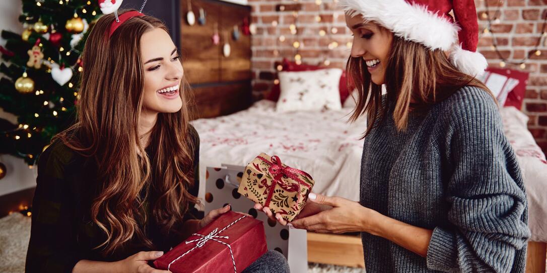 Friends presenting gifts each other in bedroom
