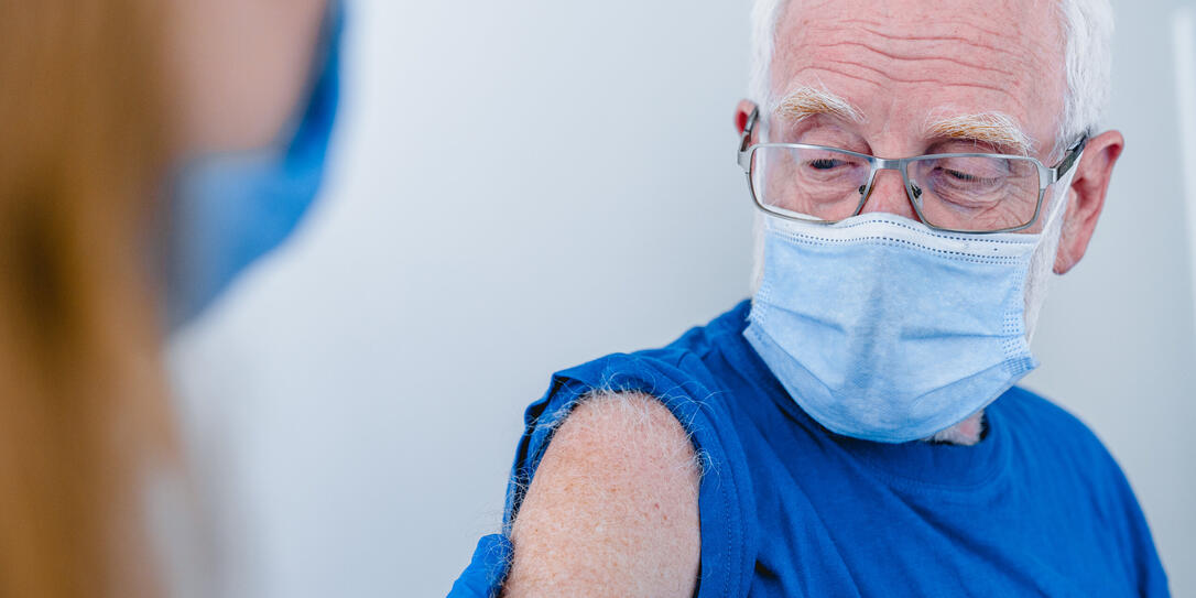 Close up photo of senior man`s arm with doctor`s hands making injection. Elderly patient wearing mask to stop coronavirus spread Close up photo of senior man`s arm with doctor`s hands making injection. Elderly patient wearing mask to stop coronavirus spread