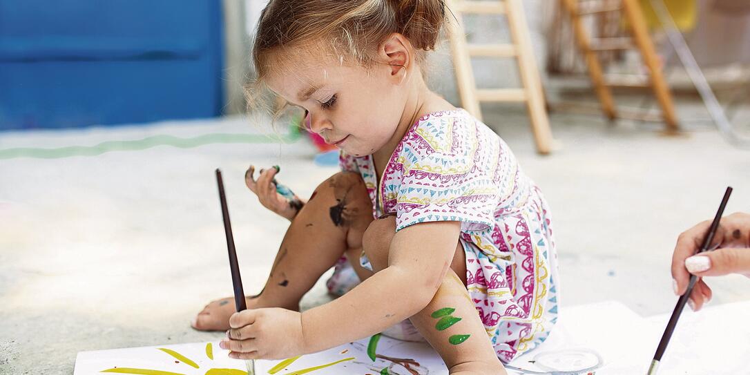 Cute little caucasian Girl enjoying Painting at the backyard with paper, water colour and art brush. Selective focus