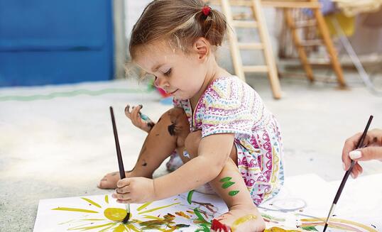 Cute little caucasian Girl enjoying Painting at the backyard with paper, water colour and art brush. Selective focus