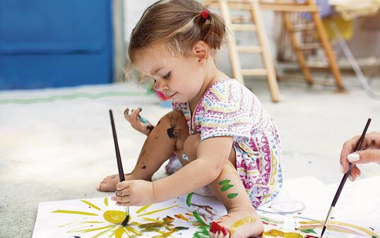 Cute little caucasian Girl enjoying Painting at the backyard with paper, water colour and art brush. Selective focus