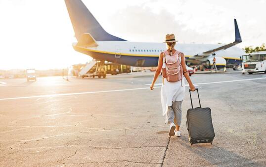 Back view of a woman walking towards the plane, ready to board and begin her vacation