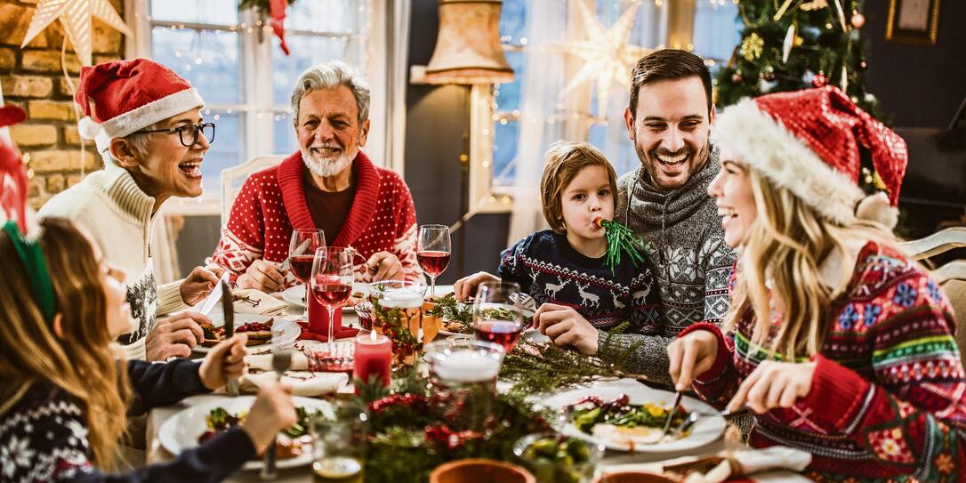 Happy extended family having New Year's lunch at dining table.