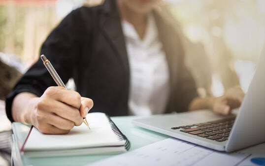 Young asia student study in the public library, She making note on notebook and using laptop