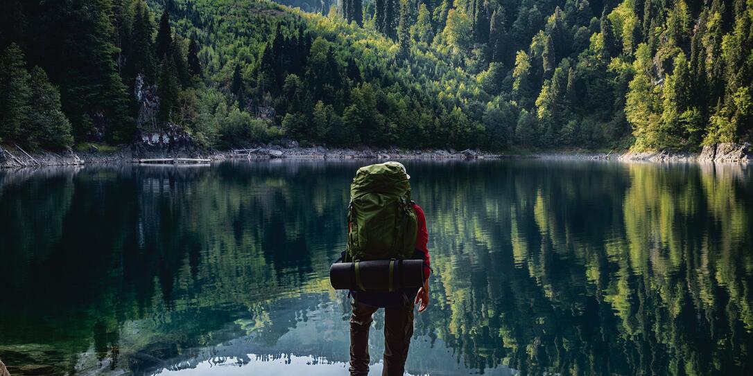 Tourist with backpack at mountain lake background