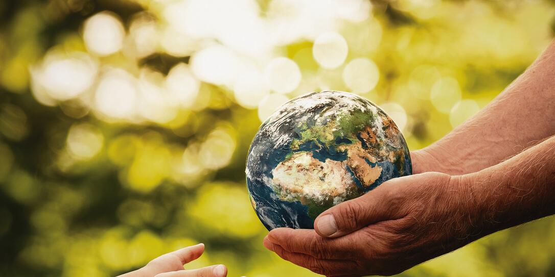 Senior hands giving small planet earth to a child Senior hands giving small planet earth to a child