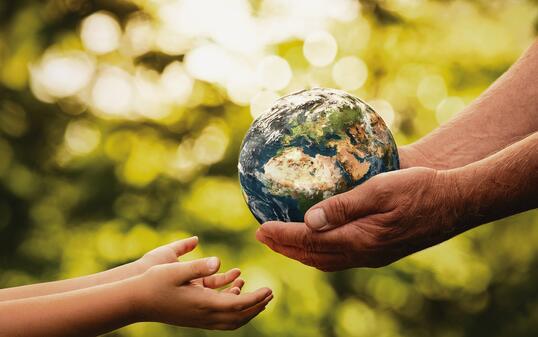 Senior hands giving small planet earth to a child