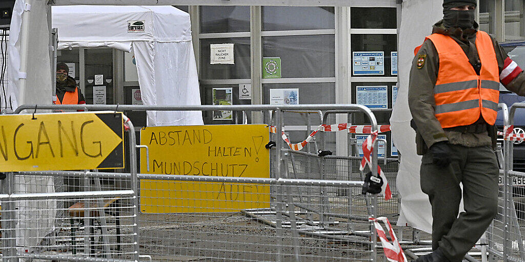 Ein Mann in Warnweste steht vor dem Eingang einer Teststelle in einer Schule in Perchtoldsdorf in Niederösterreich. Foto: Hans Punz/APA/dpa