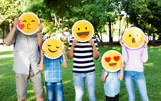 Happy family holding up emojis