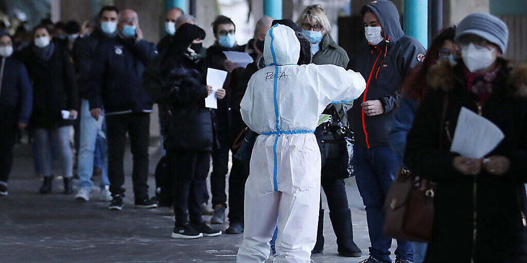 Menschen stehen vor einer Corona-Schnelltest-Einrichtung in Bozen Schlange. Foto: Antonio Calanni/AP/dpa