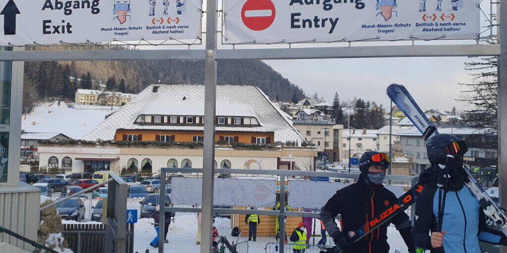 HANDOUT - Skifahrer gehen in Semmering unter Schildern, die auf die coronabedingten Hygieneregeln hinweisen, durch. Foto: Semmering-Hirschenkogel Bergbahn/APA/dpa - ACHTUNG: Nur zur redaktionellen Verwendung und nur mit vollständiger Nennung des vorstehenden Credits