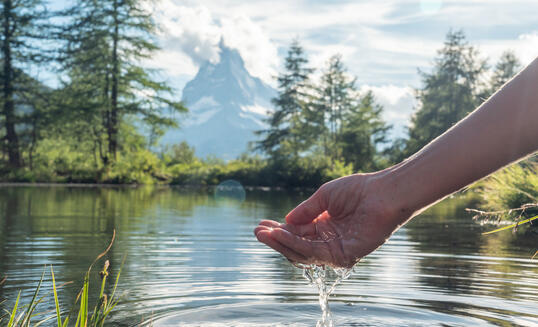 Hands scooping water from alpine lake