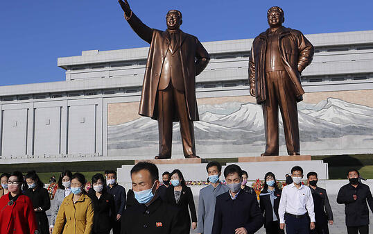 Menschen mit Maske besuchen den Mansu-Hügel, um vor dem Großmonument Mansudae, welches die zwei verstorbenen nordkoreanischen Machthaber Kim Il-sung (l) und Kim Jong-il zeigt, anlässlich des 75. Jahrestages der Gründung der Arbeiterpartei des Landes, Blumen niederzulegen. Foto: Cha Song Ho/AP/dpa