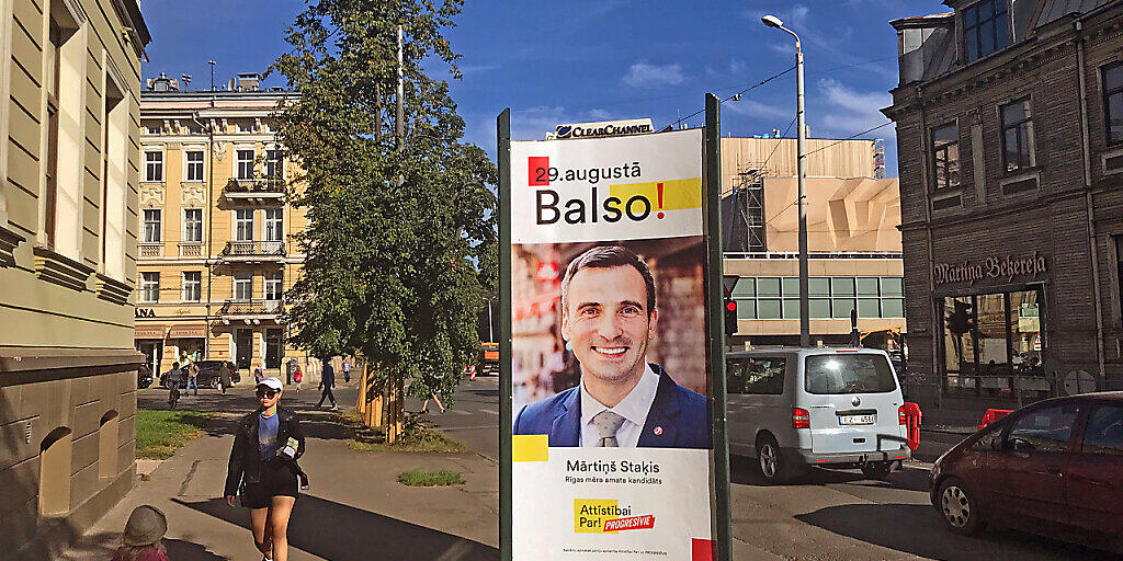 Ein Wahlplakat der gemeinsam antretenden liberalen Parteien Für die Entwicklung / Dafür! und Progressive mit einem Porträt ihres Bürgermeisterkandidaten Martins Stakis steht in der Hauptstadt. Foto: Alexander Welscher/dpa - ACHTUNG: Nur zur redaktionellen Verwendung im Zusammenhang mit einer Berichterstattung über Kommunalwahl