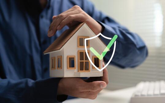 Home warranty and property protection concept with house model, protective hands, shield and check mark, representing home insurance, coverage, security, repair protection and homeowner peace of mind.