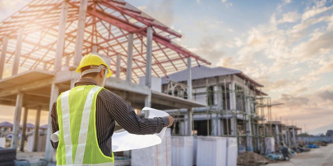 Professional engineer architect worker with protective helmet and blueprints paper at house building construction site