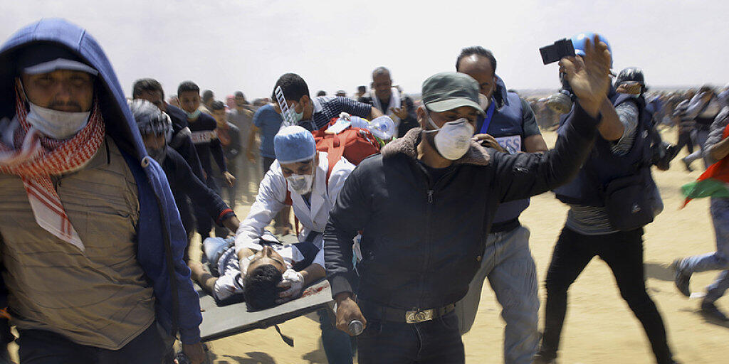 Während den blutigen Zusammenstössen im Gazastreifen an der Grenze zu Israel: Palästinensische Rettungskräfte und Protestierende transportieren einen schwerverletzten Jugendlichen auf einer Bahre. Der heutige Montag ist der Tag mit den meisten Todesopfern seit dem Gaza-Krieg 2014.