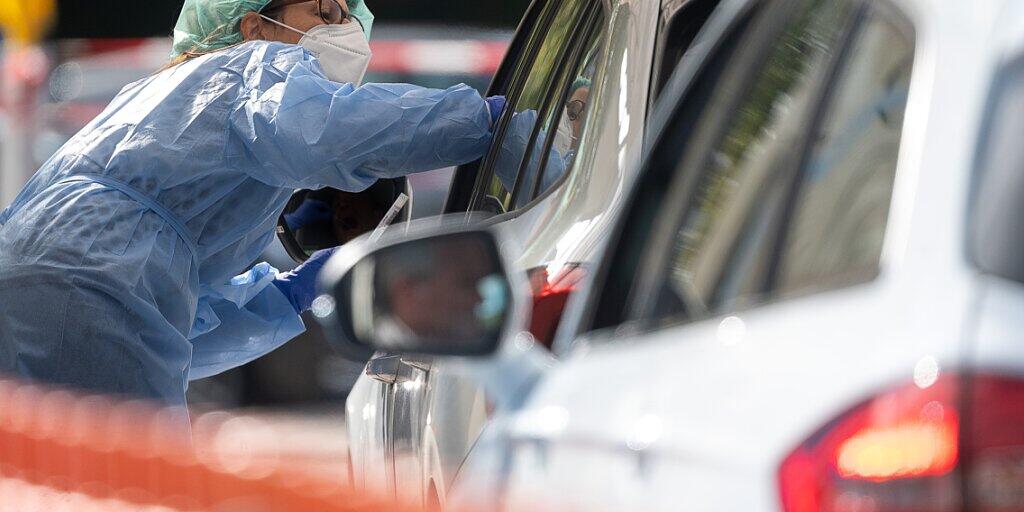 Eine Mitarbeiterin im Landkreis Esslingen macht im Corona-Abstrich-Zentrum bei einem Autofahrer einen Abstrich. Foto: Sebastian Gollnow/dpa