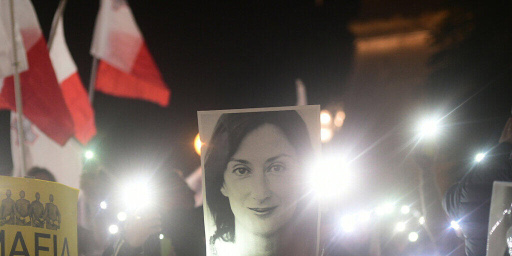 Demonstranten vor dem Büro des Ministerpräsidenten Joseph Muscat halten ein Bild der ermordeten Journalistin Daphne Caruana Galizia, die über Korruption in Malta berichtet hatte. Nun droht ein Zeuge mehrere Minister und Muscats Ex-Stabschef Keith Schembri zu belasten. (Foto: Str/AP Keystone)