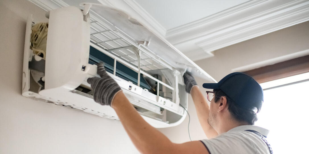 Technician repairing air conditioner at home