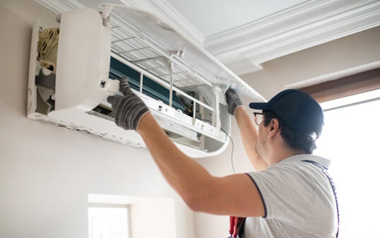 Technician repairing air conditioner at home