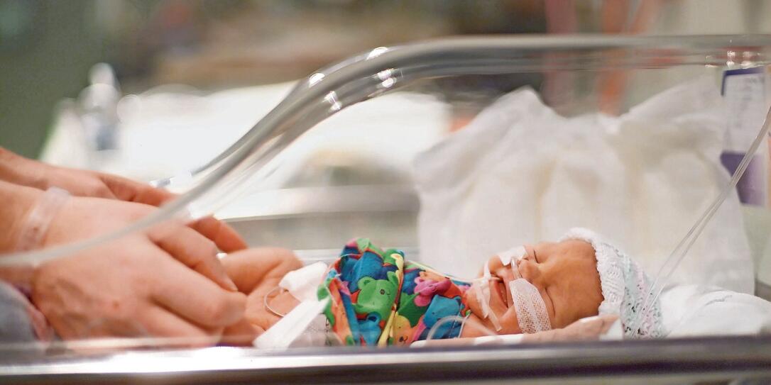 Side view of an incubator with a crying premature baby