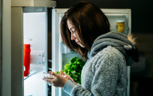 Young girl at night in front of a refrigerator