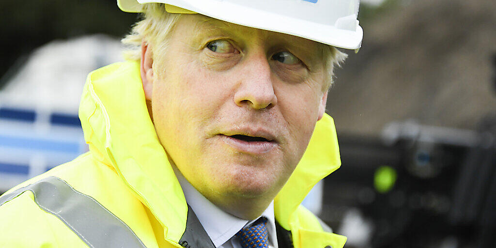 Boris Johnson, Premierminister von Großbritannien, trägt während seines Besuchs auf der Baustelle der Recycling-Firma «Conway Heathrow Asphalt Recycling Plant», einen Helm. Foto: Alberto Pezzali/AP Pool/dpa