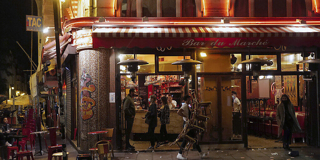 Ein Kellner räumt die Terrasse eines Restaurants vor der nächtlichen Ausgangssperre gegen die Ausbreitung des Coronavirus. Foto: Francois Mori/AP/dpa