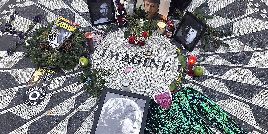 Fotos, Blumen und Kerzen stehen auf der Gedenkstätte Strawberry Fields im Central Park zur Erinnerung an John Lennon. Vor genau 40 Jahren wurde der Beatles-Musiker in New York erschossen. Der Mörder sitzt bis heute im Gefängnis. Foto: Mark Lennihan/AP/dpa