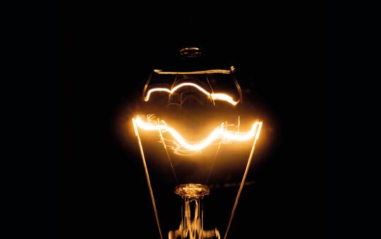 Close up of a vintage light bulb with glowing filament isolated on black background