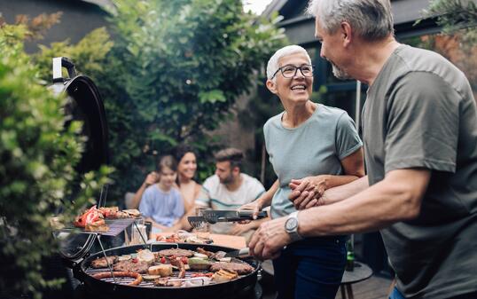 Happy senior couple enjoying making barbecue for their family