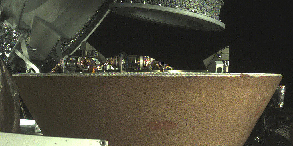 Der Sammelbehälter (rund, gelocht) schwebt über der Probenkapsel in der Raumsonde Osiris-Rex. Nachdem der Behälter wegen undichtem Deckel Teile des eingesammelten Staubs verloren hat, wurde der Rest jetzt erfolgreich gesichert. (Bild Nasa)