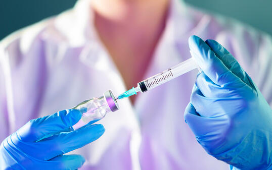 female Doctor hand holding syringe and covid-19 vaccine in blue gloves with white coat. Disease injection concept.