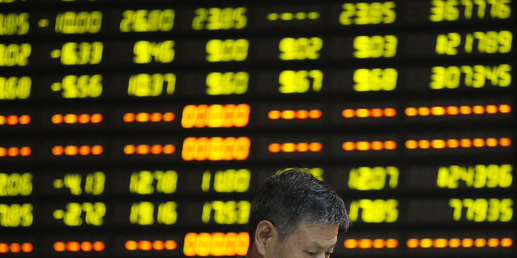 Ein Chinese steht niedergeschlagen vor einer Digitalanzeige mit Börsendaten - die chinesische Regierung will nach dem Taucher der Börse mit Stützkäufen eingreifen. (Symbolbild)