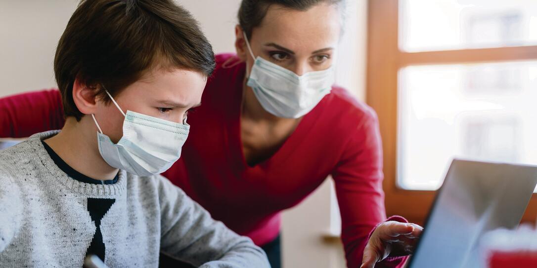 Mother and son in video chat with teacher wearing masks