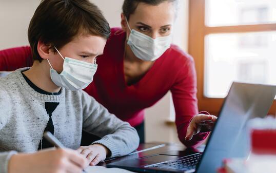 Mother and son in video chat with teacher wearing masks