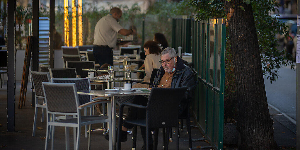 Ein Mann liest auf der Terrasse eines Cafés in Barcelona. Foto: David Zorrakino/EUROPA PRESS/dpa