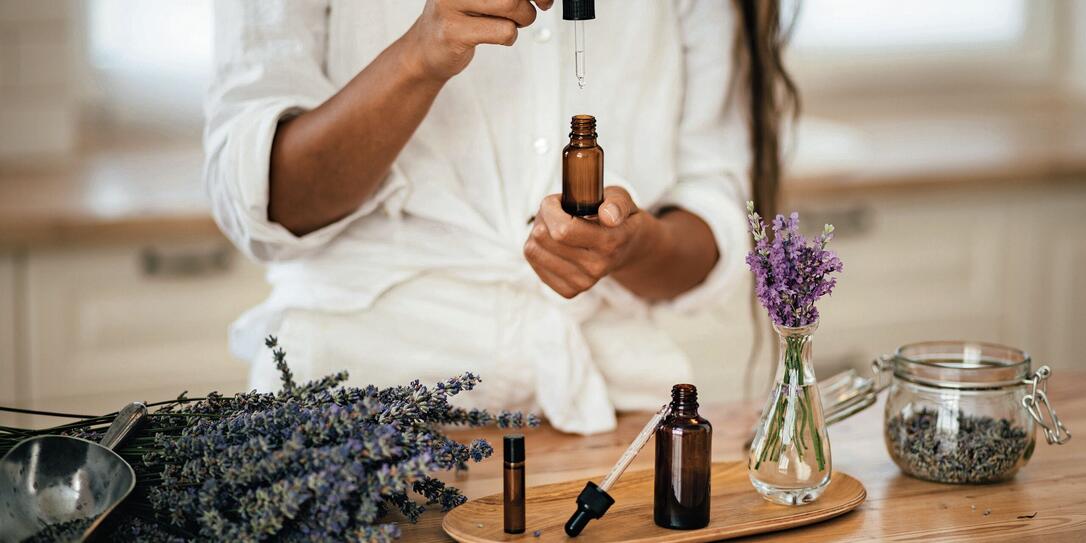 Young woman applying natural organic essential oil on hair and skin. Home spa and beauty rituals.