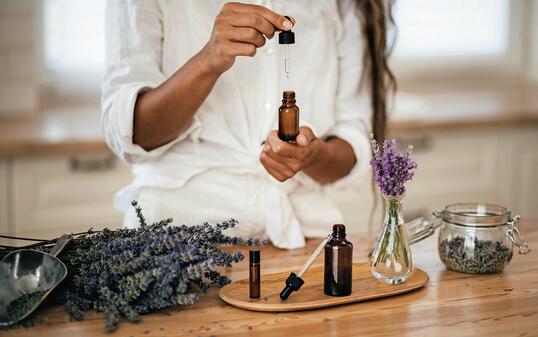 Young woman applying natural organic essential oil on hair and skin. Home spa and beauty rituals.