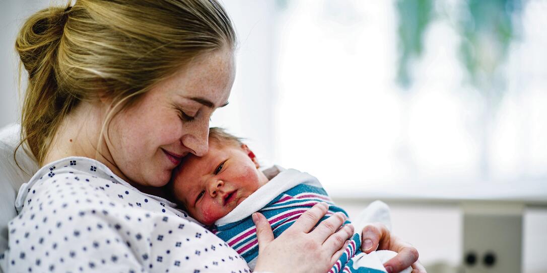 New mom holds her baby in hospital bed