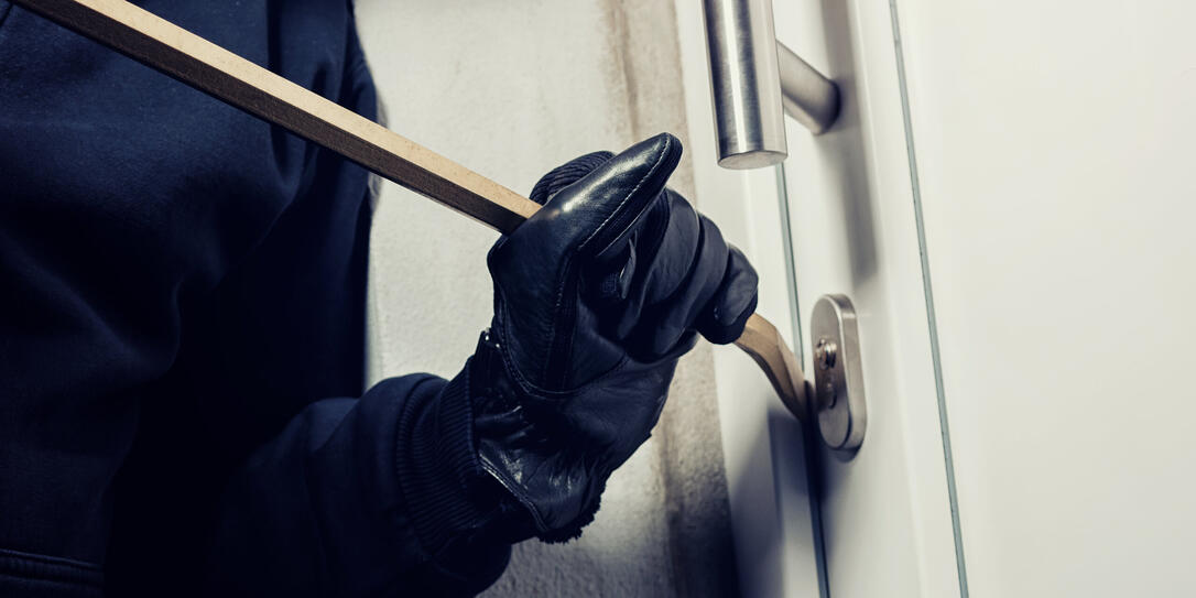 burglar using crowbar to break a home door at night