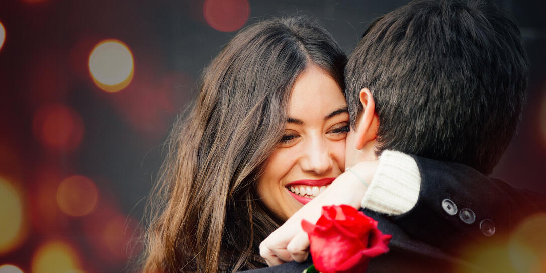 Happy couple in love with a rose embracing on the street
