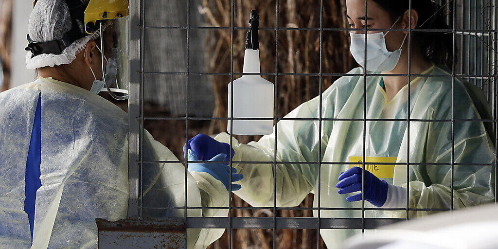 Medizinisches Personal bereitet sich auf die Durchführung eines Coronavirus-Tests bei einem Autoinsassen vor. Die Gesundheitsbehörden in Neuseeland bemühen sich, die Quelle eines neuen Ausbruchs des Coronavirus im ganzen Land ausfindig zu machen. Foto: Mark Baker/AP/dpa